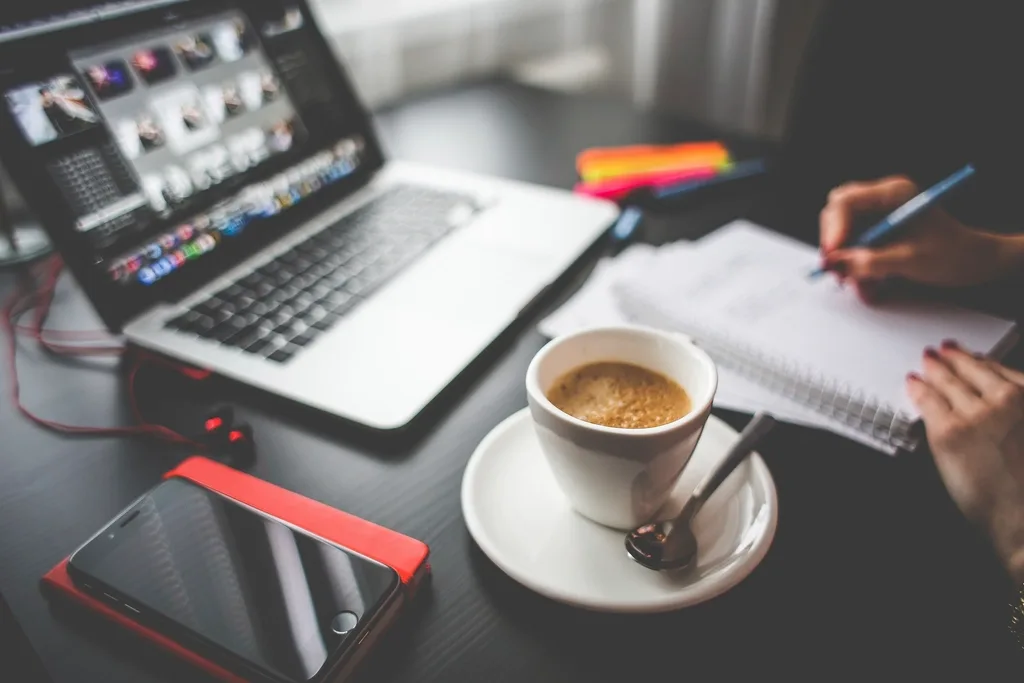 A cup of coffee beside notes on a work table while planning a content calendar