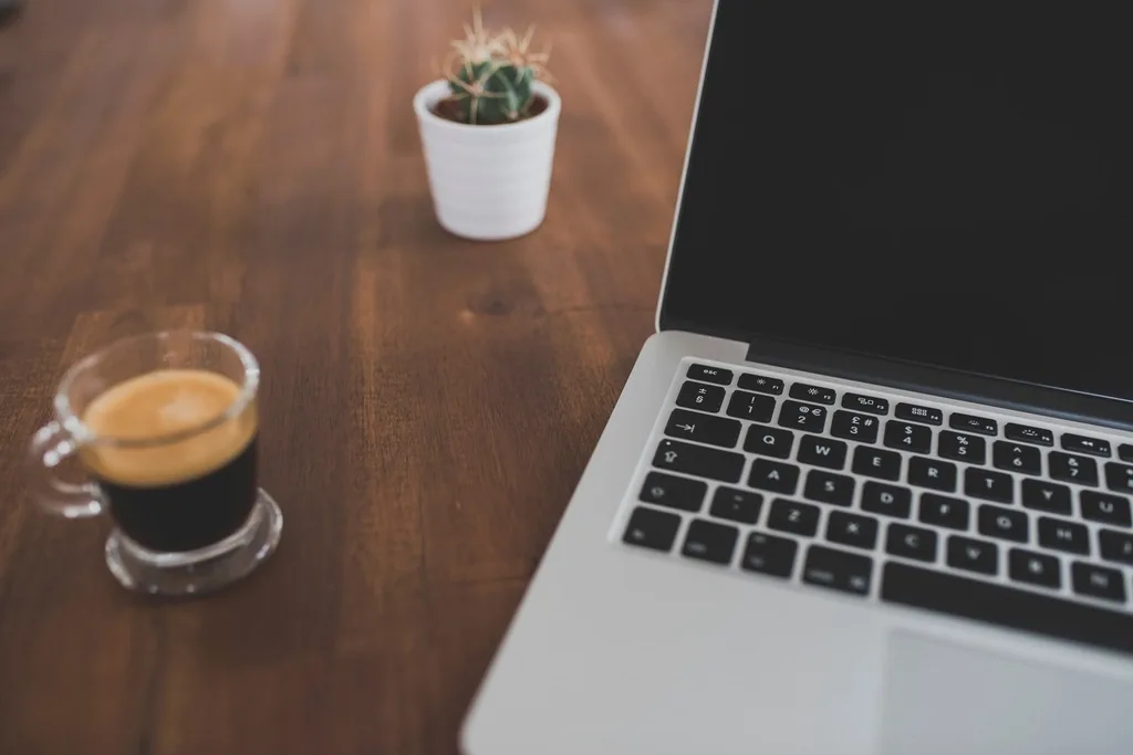 Desk with a laptop, notes and a cup of coffee, set up for planning a content calendar